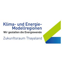 Das Logo für Klima- und Energie-Modellregionen. Es steht geschrieben, 'Wir gestalten die Energiewende, Zukunftsraum Thailand.' Eine grüne und blaue geometrische Form ist vorhanden.