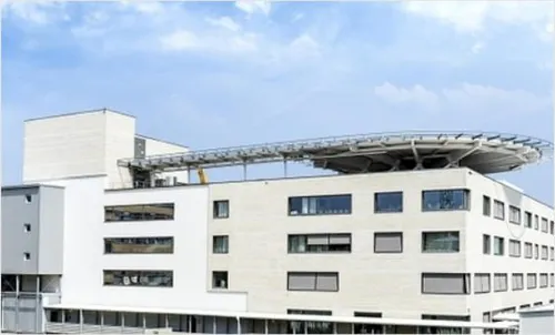 Ein modernes weißes Gebäude mit Glasfenstern und einem gebogenen Dach auf der Oberseite unter einem blauen Himmel mit Wolken.
