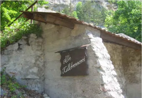 Ein altes Steingebäude mit einem Schild 'Gille Kaldebrenner' an der Wand. Das Schild ist an der Wand befestigt. Hinter dem Gebäude befinden sich Bäume.
