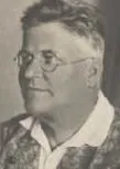 Ein altes Schwarz-Weiß-Foto eines Mannes mit einer gemusterten Bluse und einer Brille, der leicht lächelt.