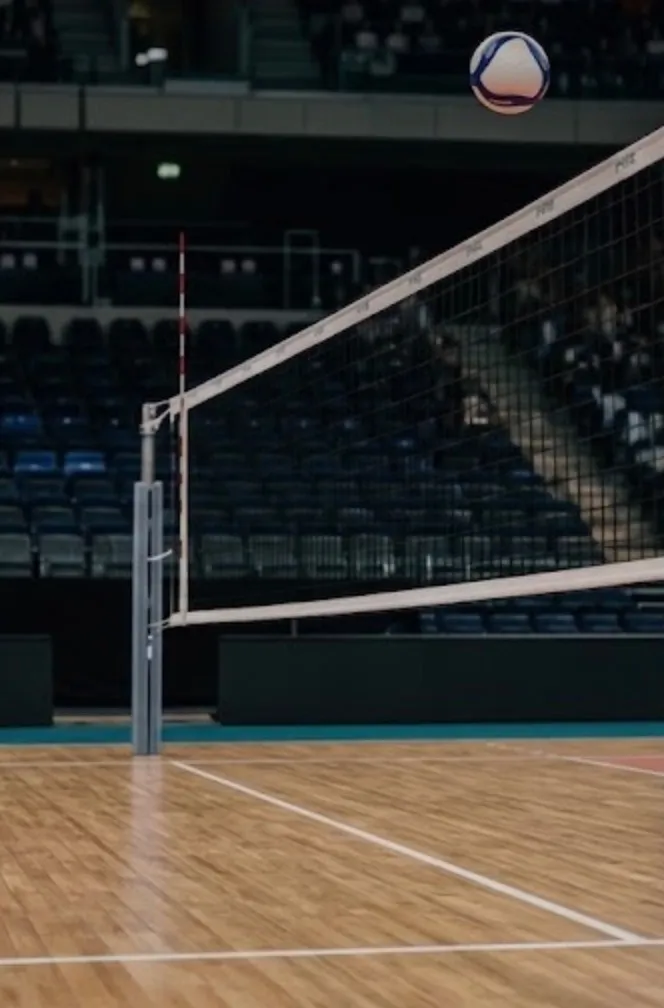 Abschnittsbild: Eine leere Indoor-Volleyballhalle mit einem Netz in der Mitte und leeren Tribünen auf beiden Seiten.