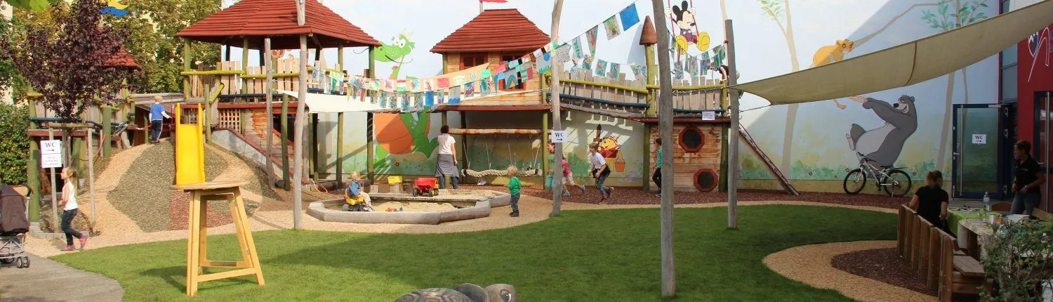 Ein farbenfroher Spielplatz mit bunten Dekorationen, einem Micky-Maus-Wandbild und Kindern, die verschiedene Aktivitäten ausüben.