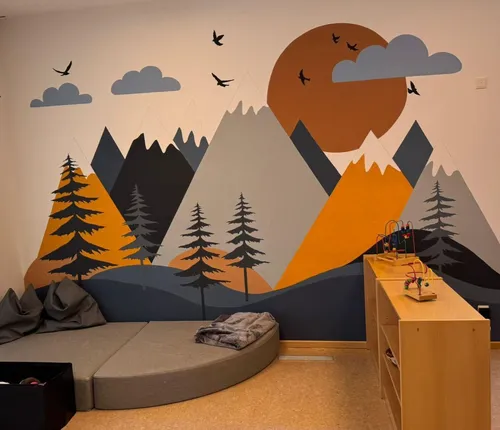 Ein Zimmer mit einer Wandmalerei von Bergen, Bäumen und Vögeln. Eine gebogene Couch mit Kissen und einer Decke. Ein Holzregal mit Spielzeug.