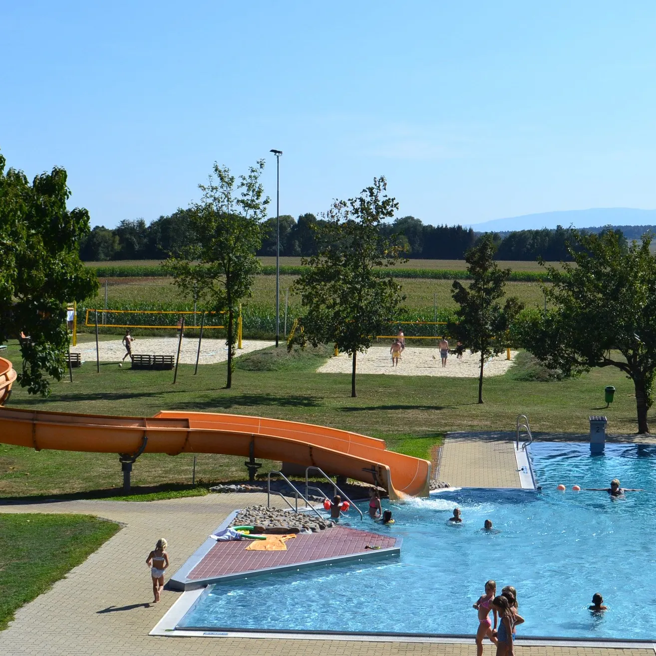 Ein Luftbild eines Wasserparks mit einer großen Rutsche und einem Pool, in dem Menschen schwimmen.