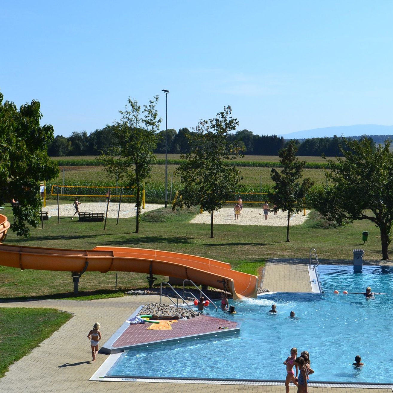 Ein Luftbild eines Wasserparks mit einer großen Rutsche und einem Pool, in dem Menschen schwimmen.
