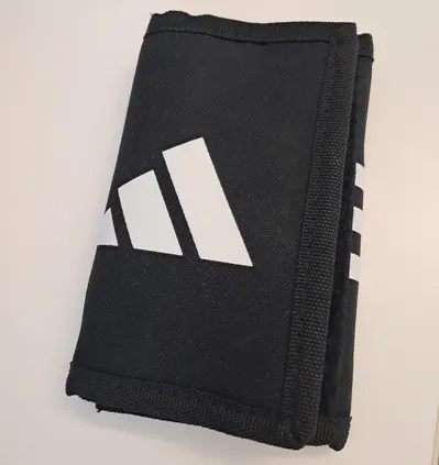 Eine schwarze Adidas-Geldbörse mit weißen Streifen und dem Adidas-Logo darauf.