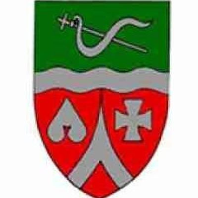 Ein Wappen zeigt einen roten und weißen Schild mit einem Kreuz und einem Spielkartensymbol. Über dem Schild befindet sich ein grüner Streifen mit einer weißen Wellenlinie und einem Paar gekreuzter Schwerter.