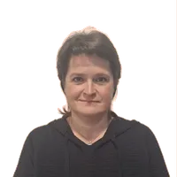 Eine Frau mit kurzen Haaren, die eine schwarze Kapuzenjacke und eine silberne Halskette trägt, lächelt direkt in die Kamera.