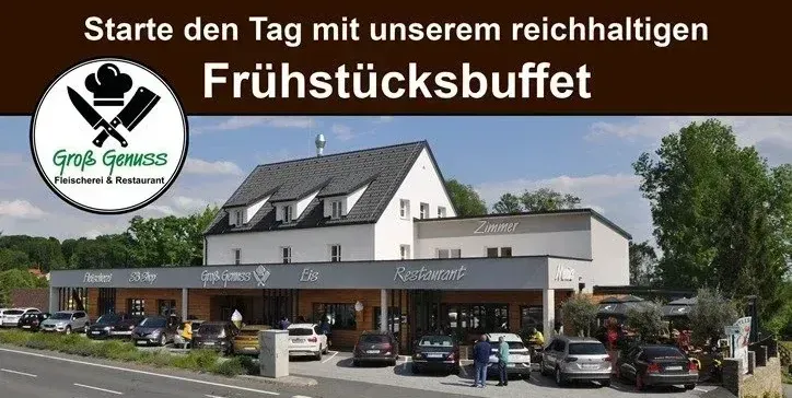 Ein Bild eines Restaurants mit einem Frühstücksbuffet-Schild, einem großen Gebäude und Autos davor. Der Himmel ist klar und blau, und es gibt Bäume im Hintergrund.