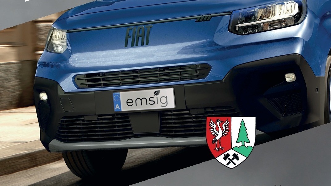 Nahaufnahme der Vorderseite eines blauen Fiat-Fahrzeugs mit Markenlogo, Kennzeichen und einer Umweltplakette der Europäischen Union. Das Kennzeichen lautet 'A emsig'.