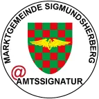 Das Bild zeigt das offizielle Siegel der Gemeinde Sigmundsherberg, das einen Schild mit grünen und roten Karos und einem goldenen geflügelten Emblem aufweist. Darunter steht der Text '@ AMTSIGNATUR'.