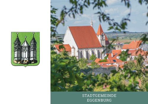 Ein malerisches Städtchen mit einer Kirche mit rotem Dach, umgeben von Bäumen und einem klaren blauen Himmel. Der Name der Stadt, Eggenburg, ist in fetter Schrift angezeigt.
