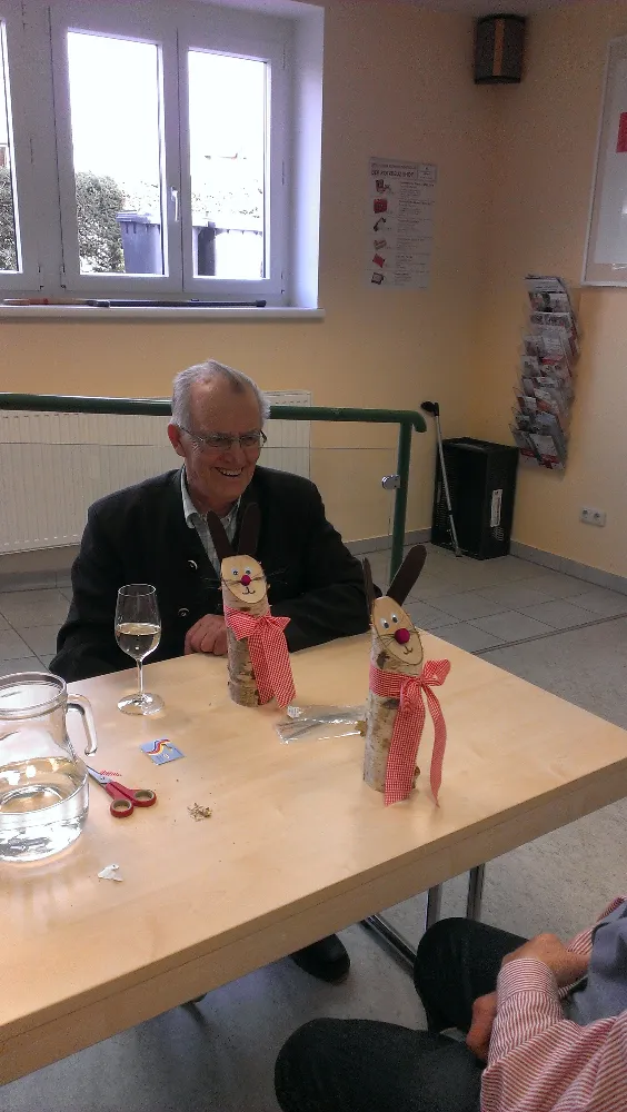 Ein Mann sitzt an einem Tisch mit einem Glas Wein und zwei Miniaturfiguren von Schneemännern auf dem Tisch.