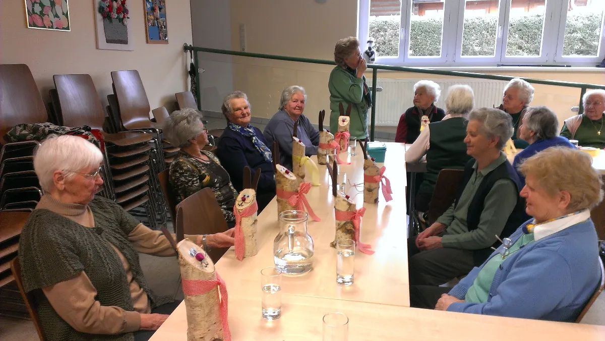 Eine Gruppe von Frauen sitzt an einem langen Tisch mit einem Tischcenterpiece aus Birkenrinde und Glas.