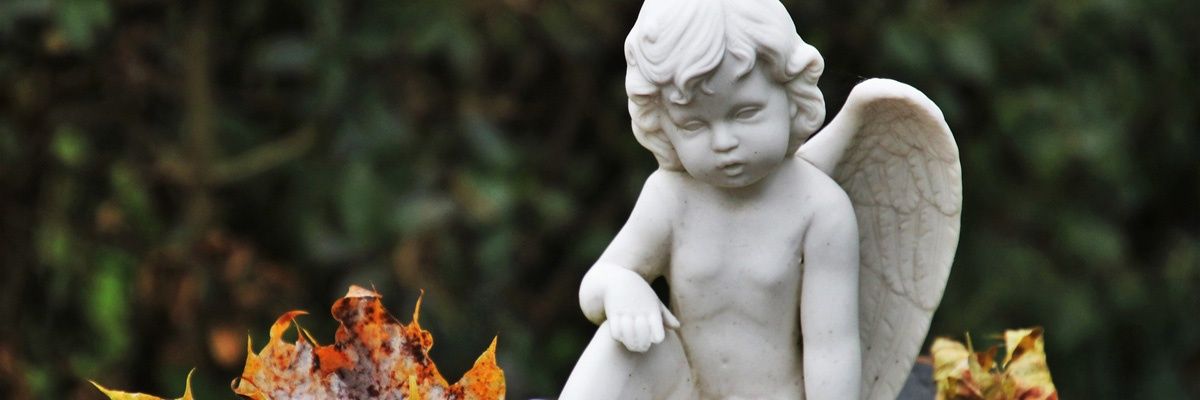 Eine weiße Marmorstatue eines Cherubs, der auf dem Boden sitzt, mit einem Blatt in der Nähe.