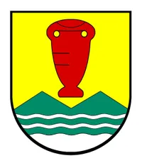 Ein heraldischer Schild mit gelbem Hintergrund, einem roten vaseartigen Objekt oben und einem grünen Bergrücken mit wellenförmigen weißen Linien unten.