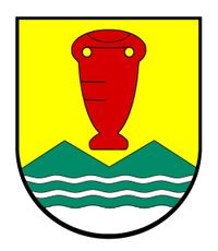 Ein heraldischer Schild mit gelbem Hintergrund, einem roten vaseartigen Objekt oben und einem grünen Bergrücken mit wellenförmigen weißen Linien unten.