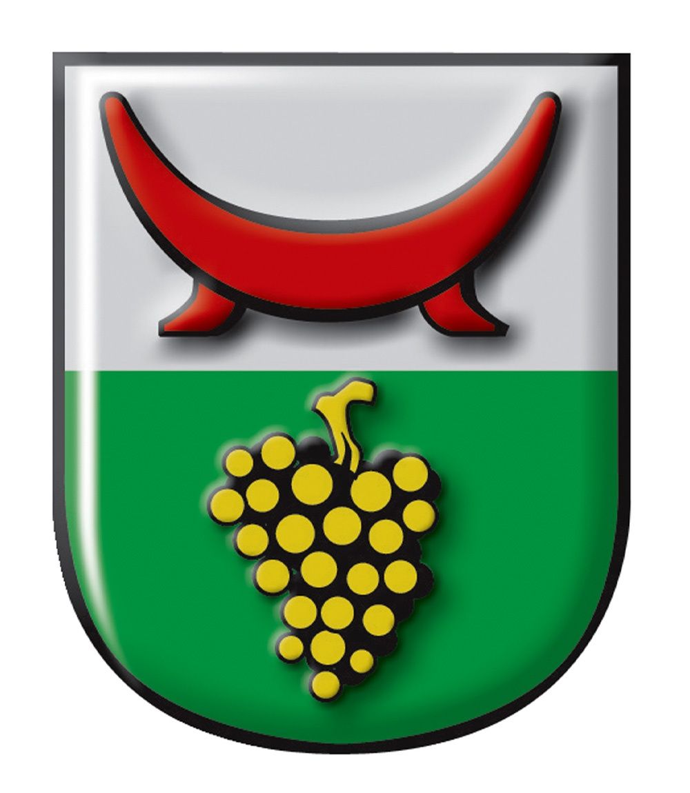 Ein schildförmiges Emblem mit einem roten Halbmond oben und einem Strauß gelber und schwarzer Trauben in der Mitte auf grünem Hintergrund.