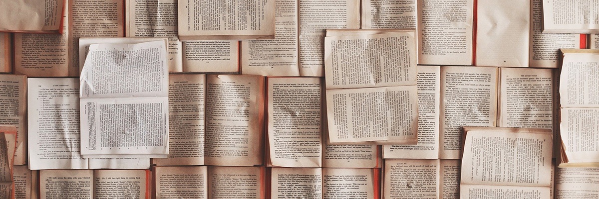 Eine Nahaufnahme von mehreren Büchern, die aufeinandergestapelt sind und Seiten mit Text sowie einige mit leeren Stellen zeigen. Die Bücher sind in verschiedenen Größen und Farben, einige erscheinen alt und abgenutzt.