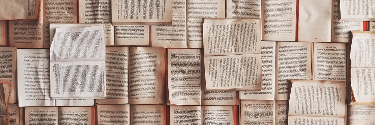 Eine Nahaufnahme von mehreren Büchern, die aufeinandergestapelt sind und Seiten mit Text sowie einige mit leeren Stellen zeigen. Die Bücher sind in verschiedenen Größen und Farben, einige erscheinen alt und abgenutzt.