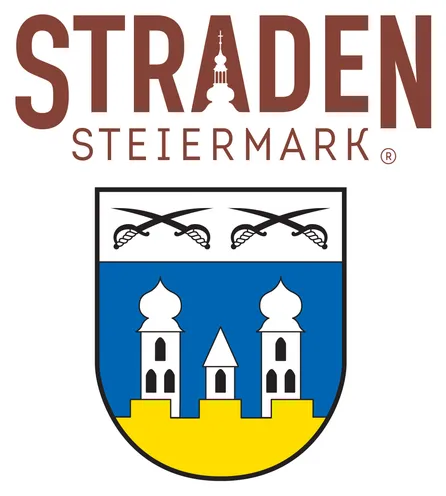 Das Logo für Straden Steiermark zeigt einen Schild mit zwei weißen Türmen auf einem gelben Sockel, vor blauem Hintergrund, und zwei gekreuzten Schwertern darüber.