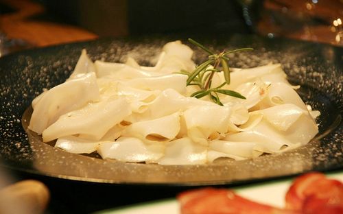 Ein Teller mit cremiger Pasta und einem Rosmarinzweig als Garnierung. Die Pasta ist mit einer Tomatenscheibe garniert.