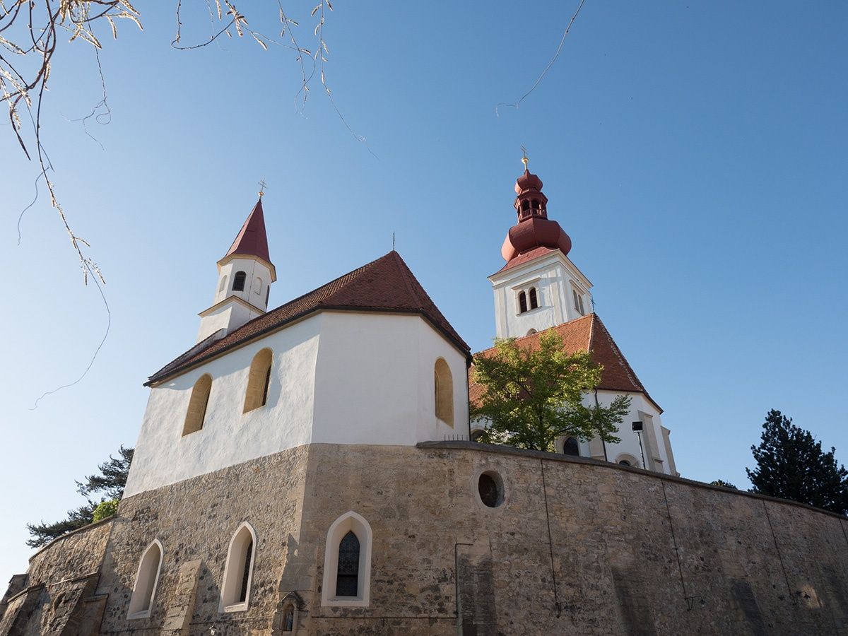 Eine Kirche mit zwei Türmen, einer mit einem roten Dach und der andere mit einem weißen Dach. Die Kirche ist weiß gestrichen und hat ein braunes Dach.