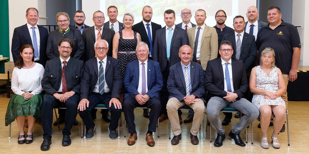Eine Gruppe formell gekleideter Personen, darunter Männer und Frauen, posiert für ein Foto in einem Konferenzraum. Sie sitzen und stehen, einige tragen Krawatten und Brillen.
