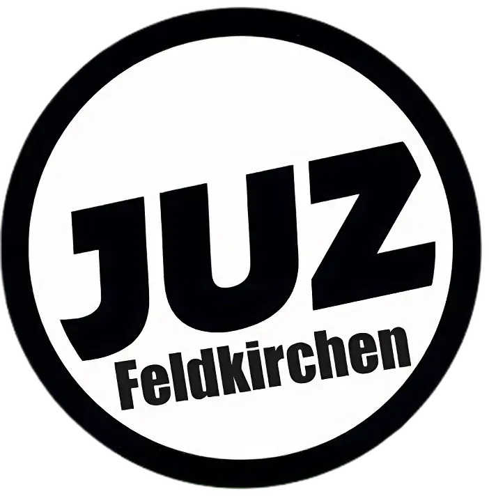 Ein rundes schwarzes und weißes Logo mit dem Wort 'JUZ' in fetten schwarzen Buchstaben über dem Wort 'Feldkirchen' in einer kleineren Schrift.