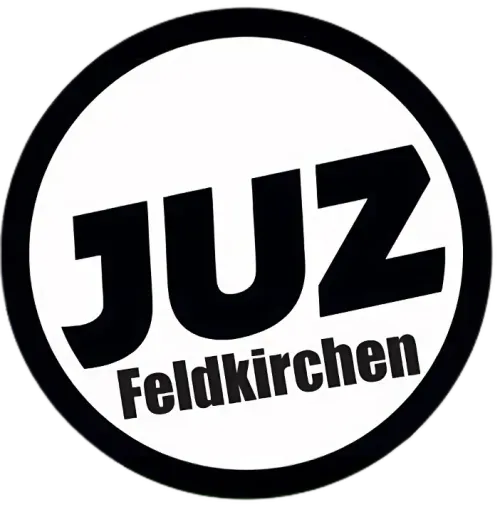 Ein rundes schwarzes und weißes Logo mit dem Wort 'JUZ' in fetten schwarzen Buchstaben über dem Wort 'Feldkirchen' in einer kleineren Schrift.