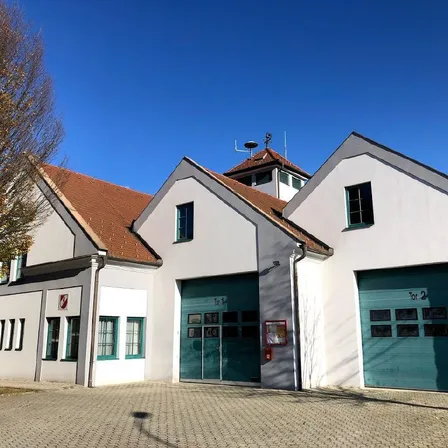 Eine Feuerwache mit einem roten Dach und zwei großen grünen Türen vorne.