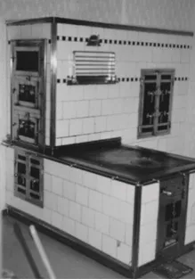 Ein Schwarz-Weiß-Foto eines altmodischen Küchenherdes mit gefliesten Wänden und einer Metalltür.