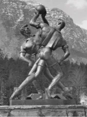 Eine Schwarz-Weiß-Statue von zwei Männern, die Basketball spielen, mit Bergen im Hintergrund.