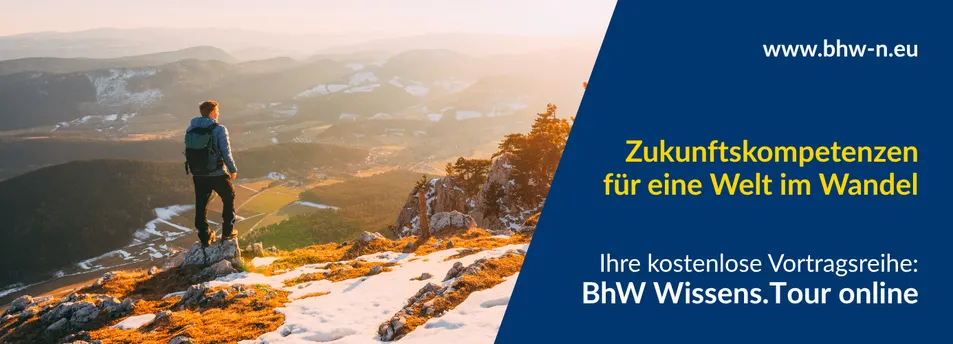 Ein Mann steht auf einem schneebedeckten Berggipfel und blickt auf eine weite Landschaft.
