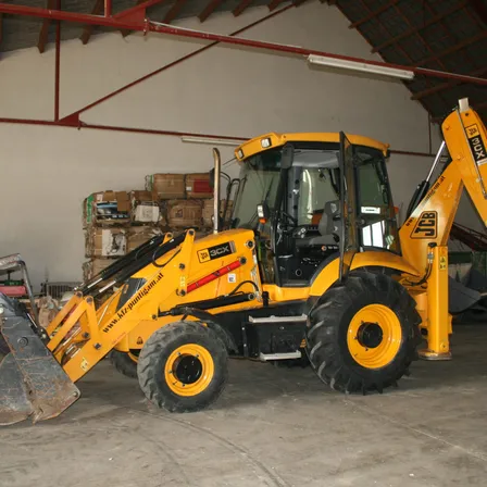 Ein gelber Bagger mit großer Schaufel und Markenlogo steht in einer Lagerhalle.