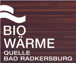 Ein hölzerner Hintergrund mit den prominent angezeigten Worten 'Bio-Wärme' und 'Quelle'. Darunter stehen die Worte 'Bad Radkersburg'. Das Design zeichnet sich durch eine wellenförmige weiße Linie als Teil des Logos aus.