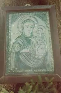 Ein Bild eines gerahmten religiösen Kunstwerks, das eine Frau mit einem Kind darstellt, auf einem Baumstumpf platziert.
