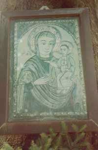 Ein Bild eines gerahmten religiösen Kunstwerks, das eine Frau mit einem Kind darstellt, auf einem Baumstumpf platziert.