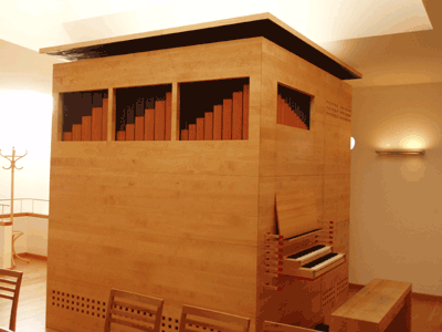Eine Orgel in einer Holzstruktur mit einer Tastatur und Bänken in einem Raum mit Stühlen und einem Tisch