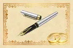 Ein silberner und schwarzer Stift mit goldener Spitze liegt auf einem beigefarbenen Hintergrund mit goldenem Rand. Zwei goldene Ringe befinden sich rechts vom Stift.