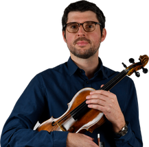 Ein Mann in einem blauen Hemd und mit Brille hält eine Geige mit einem Bogen in den Händen.