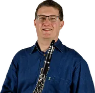 Ein Mann mit Brille und blauem Hemd hält eine Klarinette vor schwarzem Hintergrund.