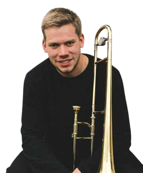 Ein Mann in einem schwarzen Shirt sitzt und lächelt, während er ein Tenorhorn hält.