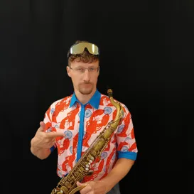 Ein Mann mit einer Mütze mit Hummern auf dem Kopf und einer Trompete in der Hand.