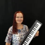 Eine Frau mit roten Haaren und einer Brille hält ein schwarzes und weißes Keyboard.
