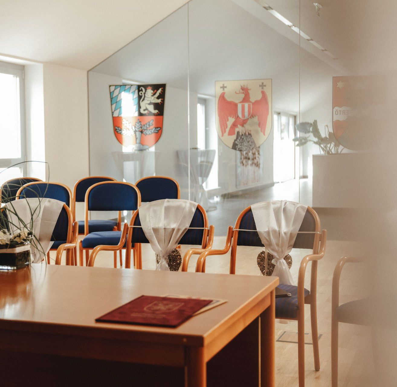 Ein leerer Besprechungsraum mit Holzstühlen und Tischen. Auf dem Tisch steht eine kleine Pflanze.