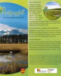 Plakat für ein Naturschutzgebiet mit einem Schwan im Teich, Bäumen und Bergen im Hintergrund. Das Plakat hat einen Wasserzeichen und Text über Vogelbeobachtungsregeln und Gebietsbeschreibung.