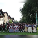 Eine Gruppe von Menschen in traditioneller deutscher Kleidung posiert für ein Foto vor einem Gebäude.