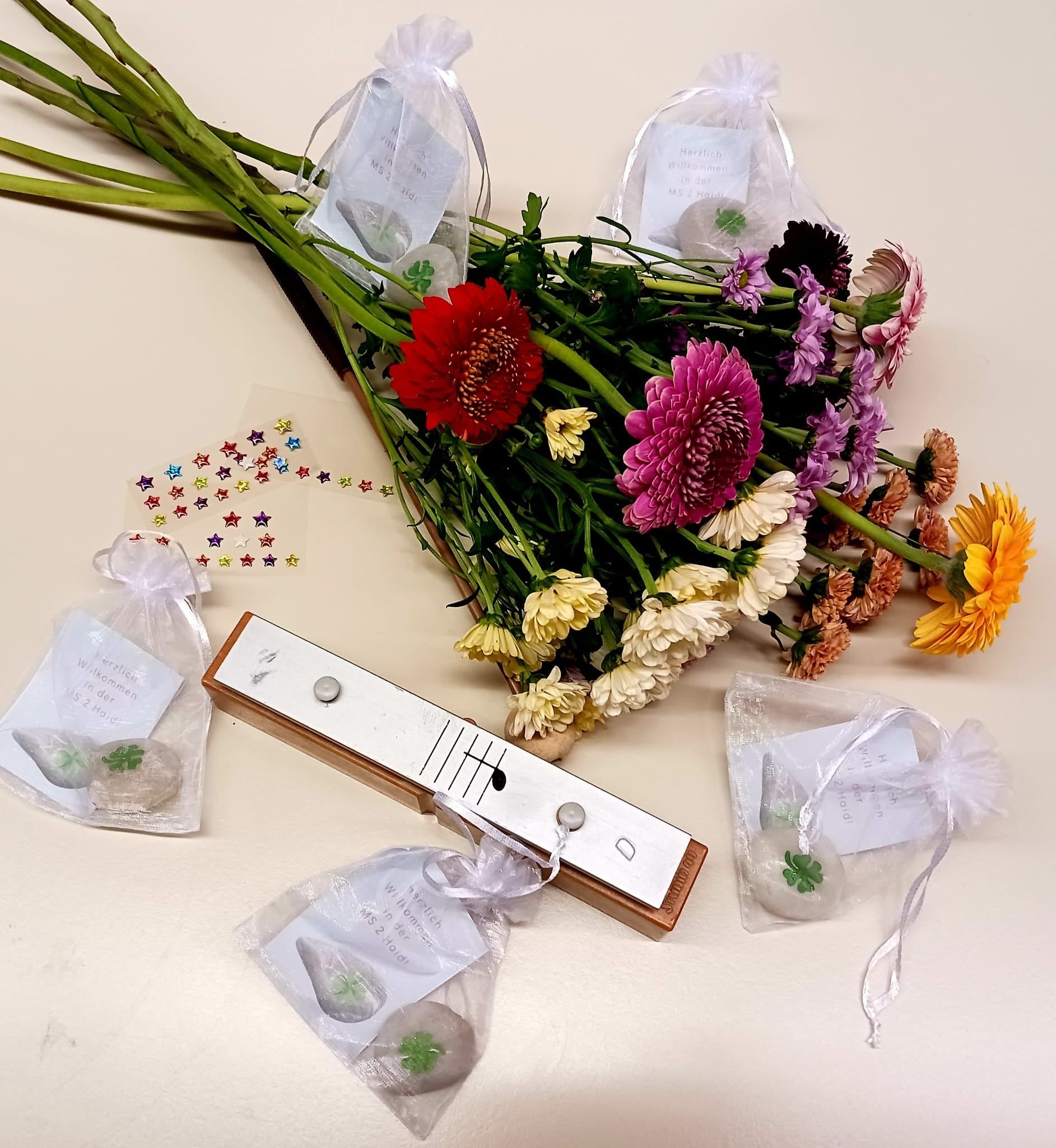 Ein Strauß bunter Blumen mit verschiedenen Dekorationsartikeln, einschließlich eines kleinen Musikinstruments und kleiner Steine in Plastiktüten.