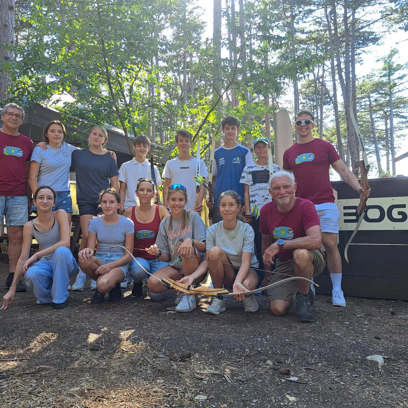 Eine Gruppe von Menschen im Wald, einige halten Bögen und Pfeile und posieren für ein Foto.